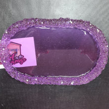 Load image into Gallery viewer, A purple glittery oval tray with a rough, sparkly rim, shown on a dark textured surface with a small pink and white tag attached.
