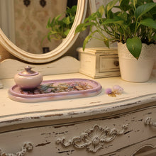 Load image into Gallery viewer, A decorative oval tray with a lavender background and fantasy artwork of a blue dragon, flowers, and steampunk elements, shown with a matching lidded cup on a dark surface. A small white animal charm with a purple pom-pom and gold keychain lies to the right.

